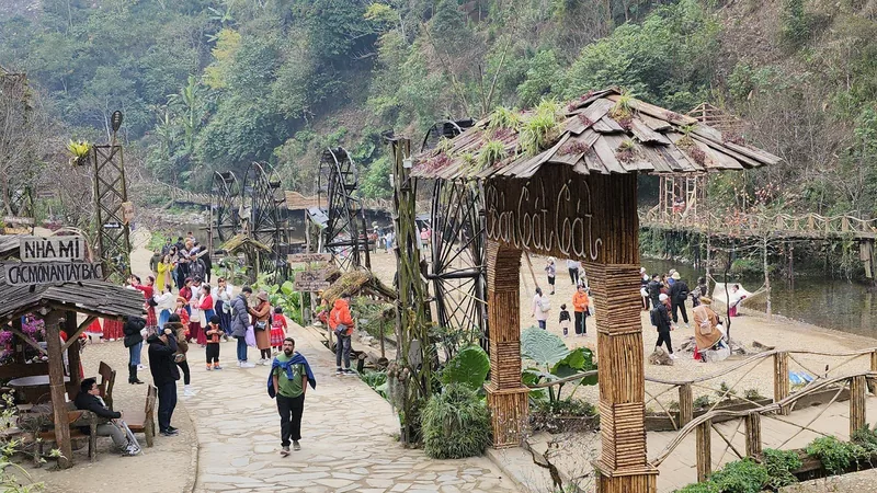 Visitors stroll past wooden waterwheels and thatched huts at Cat Cat Village entrance in Sa Pa. Visitors stroll past wooden waterwheels and thatched huts at Cat Cat Village entrance in Sa Pa.