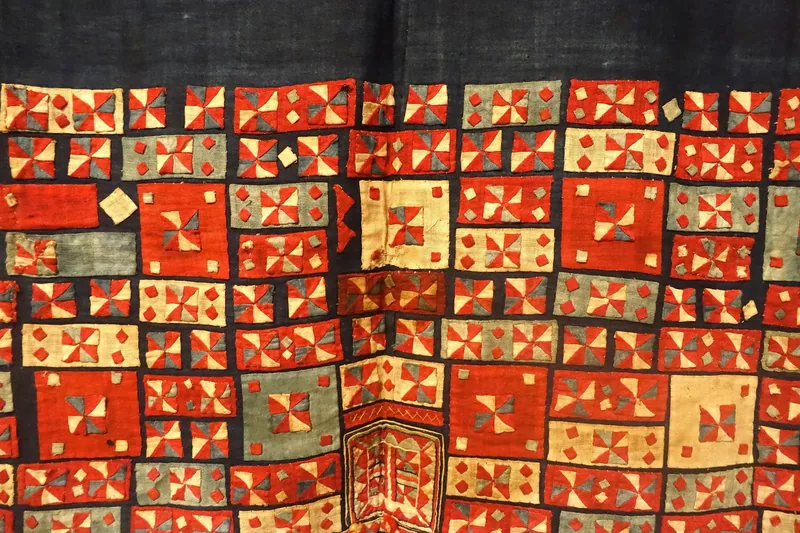 Traditional Pu Péo textile from Ha Giang features rows of red, cream, and grey geometric patchwork patterns. Traditional Pu Péo textile from Ha Giang features rows of red, cream, and grey geometric patchwork patterns.