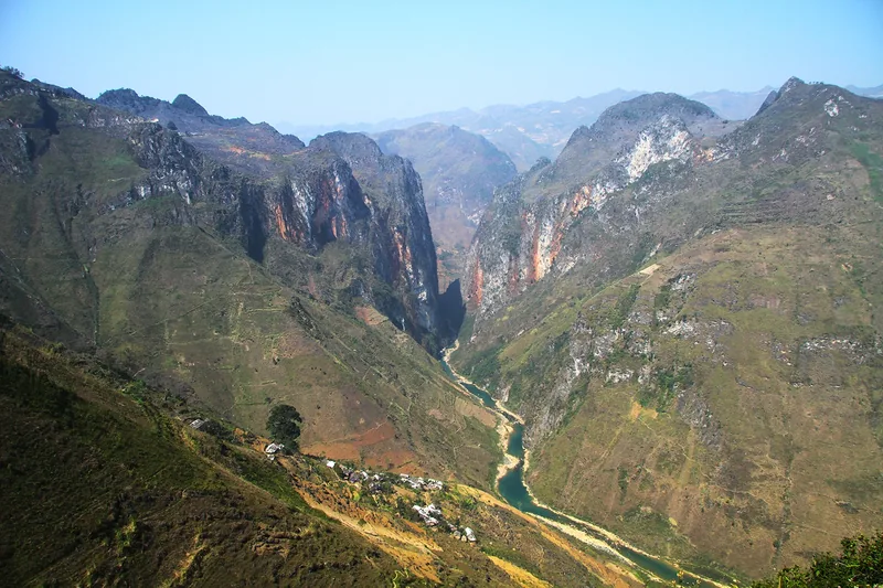 The Tu San Canyon in Ha Giang cuts a deep gorge with the Nho Que River winding below rugged limestone mountains. The Tu San Canyon in Ha Giang cuts a deep gorge with the Nho Que River winding below rugged limestone mountains.