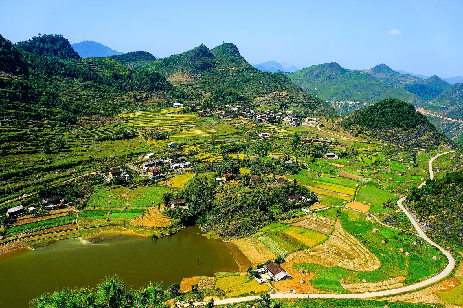 A patchwork of rice terraces, fields, and a small village fills a valley surrounded by karst mountains in Ha Giang. A patchwork of rice terraces, fields, and a small village fills a valley surrounded by karst mountains in Ha Giang.