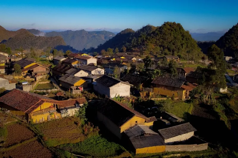 Aerial view of a mountain village with tiled-roof houses nestled among green hills in Ha Giang. Aerial view of a mountain village with tiled-roof houses nestled among green hills in Ha Giang.