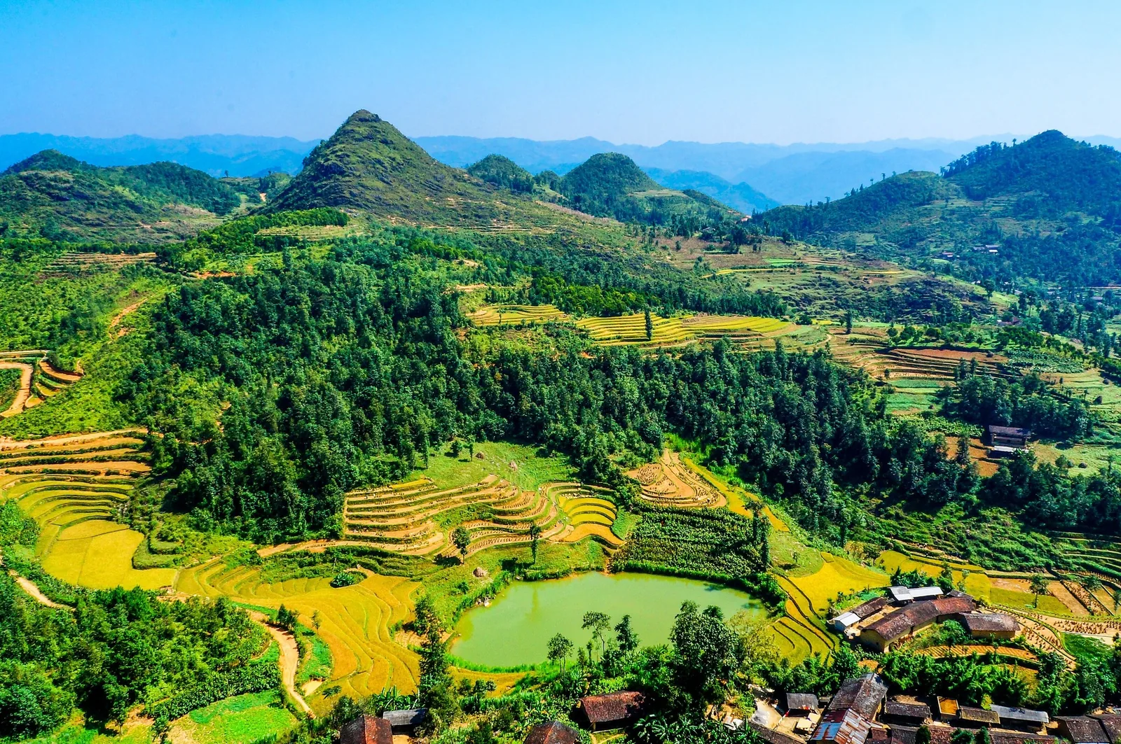 Terraced fields and a green pond spread across the mountainous valley of Ha Giang, Vietnam. Terraced fields and a green pond spread across the mountainous valley of Ha Giang, Vietnam.