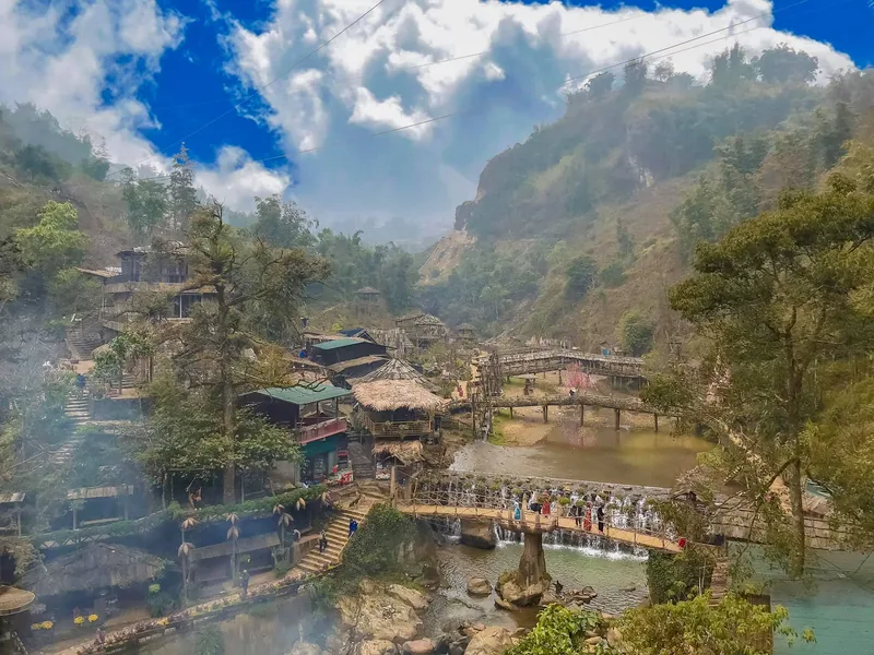 A mountain village near Sapa with thatched huts, small waterfalls and bridges over a stream surrounded by misty peaks. A mountain village near Sapa with thatched huts, small waterfalls and bridges over a stream surrounded by misty peaks.