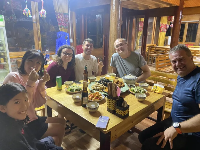 Travelers gather around a wooden table sharing a home-cooked meal at a stilt house restaurant near Fansipan, Lao Cai. Travelers gather around a wooden table sharing a home-cooked meal at a stilt house restaurant near Fansipan, Lao Cai.
