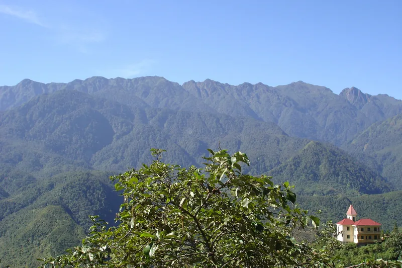A red-roofed building sits below the rugged Hoang Lien mountain range near Sapa. A red-roofed building sits below the rugged Hoang Lien mountain range near Sapa.