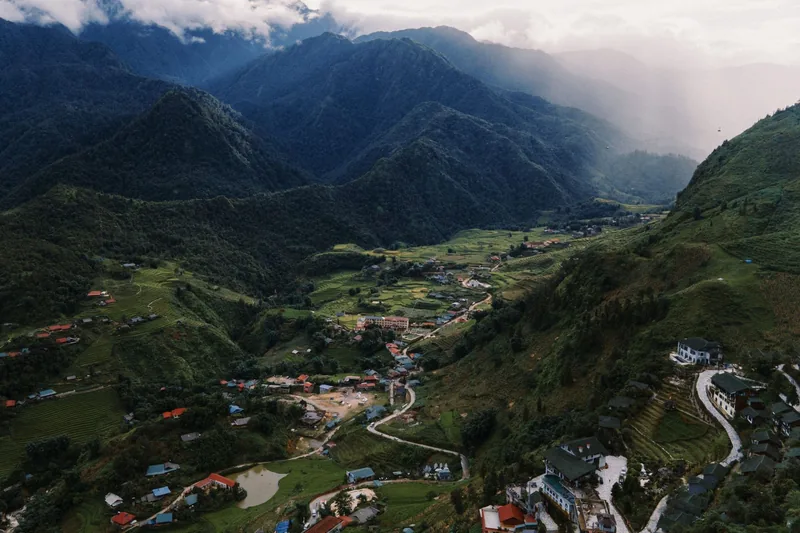 Aerial view of a valley village surrounded by misty mountains in Sapa, Vietnam. Aerial view of a valley village surrounded by misty mountains in Sapa, Vietnam.