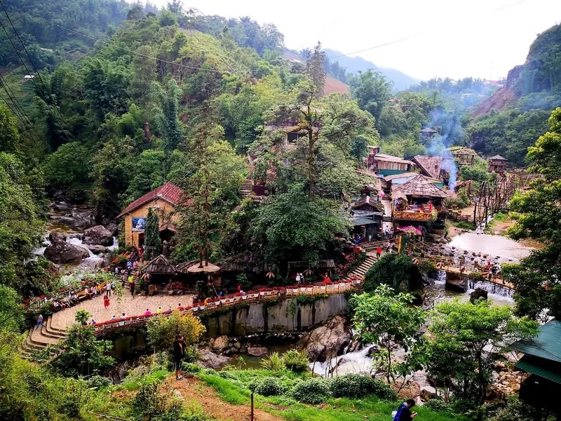 A stone pathway winds through wooden houses and streams surrounded by lush hills in Cat Cat Village, Sapa. A stone pathway winds through wooden houses and streams surrounded by lush hills in Cat Cat Village, Sapa.